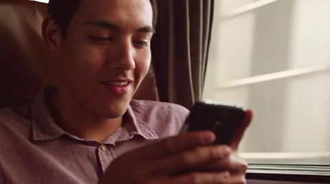 Close up of a young man using his cell phone on a train and smiling Stock Footage 57506831