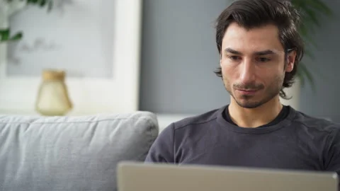 Close-up of young man using laptop at home while sitting on the sofa Stock Footage 149258069