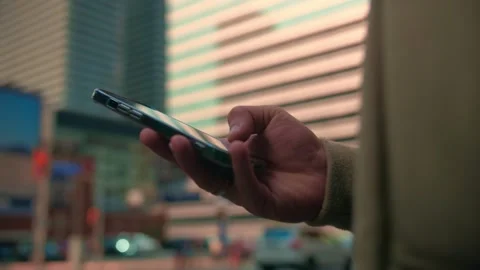 Close up of young man using phone browsing internet on city background.Guy wear Stock Footage 247297185