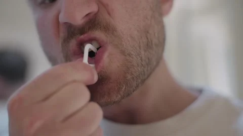 Close up of a young man using a plastic floss pick to clean between his teeth in Stock-Footage 335201159