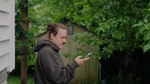 Close-up of a young man using a smartphone in a lush garden... Vídeos de archivo 339101751