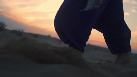 Close-up of young man walking barefoot along the dunes in the desert . 库存影片 239093480