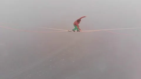 Close-up of a young man walking on a tight slackline at a high altitude above Stock Footage 151229750