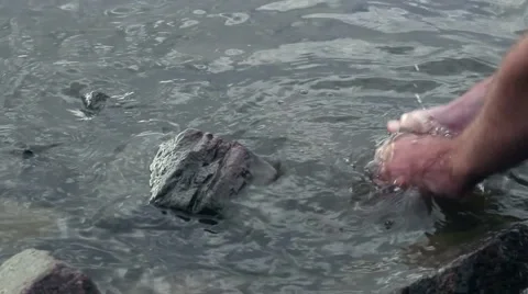 Close up of young man washes his hands in the sea  Stock Footage 66475037