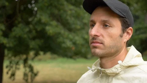 Close-up of young man wearing cap looking and smiling in park in slow motion Vídeo Stock 114874122