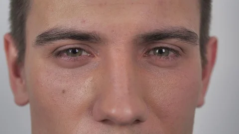 Close up of young mans eye looking into camera at isolated white background Stock Footage 130148177