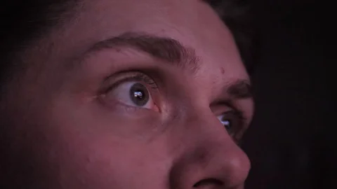 Close-up of a young man's eyes looking at screen in a deep night. Young man Stockbeeldmateriaal 128435155