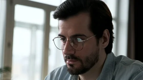 Close Up of a Young man's Face with Glasses Working at a Computer Online Stock Footage 144236527
