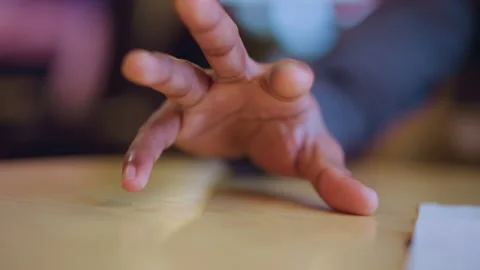 Close-up of young mans hand gently resting on table surface in soft indoor Stock Footage 318196320