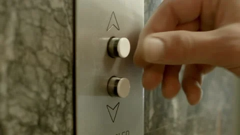 Close up of a young man's hand pushing an analog elevator button calling Stock Footage 147423976