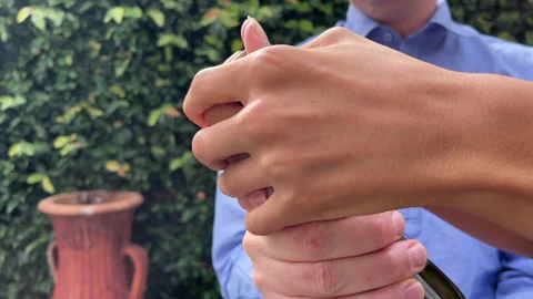 Close up of a young man's hands struggling to ease a cork out of a bottle while  Stock Footage 208160021