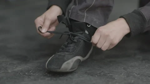 Close-up on young man's hands tying black sneaker laces in slow motion Stock Footage 231356326