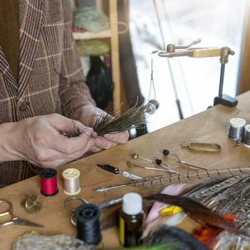 Close up on young man's hands tying a fly for fishing Stock Photos