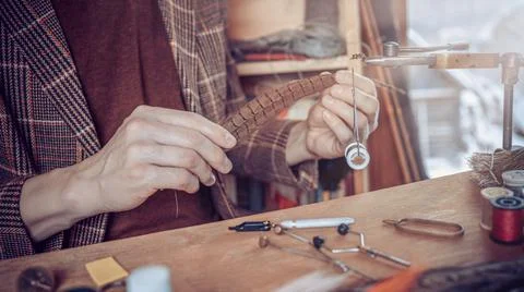Close up on young man's hands tying a fly for fishing Stock Photos