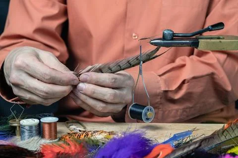 Close up on young man's hands tying a fly for fishing Stock Photos