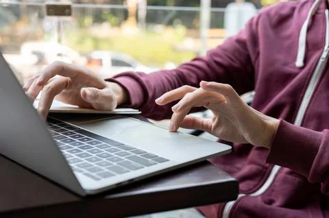 Close up of a young man's hands typing and looking at laptop while sitting .. Stock Photos