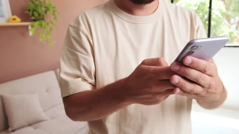 Close-up of young man's hands using mobile phone in the living room Stock Footage 250840836