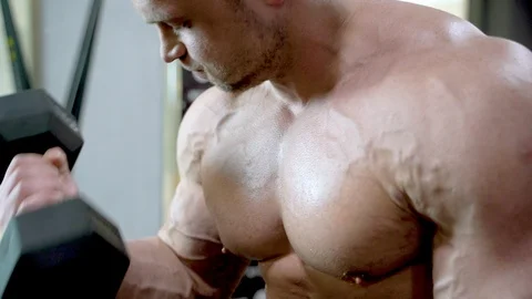 Close-up of a young muscular man doing exercises with dumbbells. Stock Footage 107427470