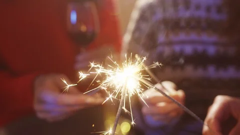 Close-up young people standing in circle lighting up sparklers for festive Stock Footage 121593359