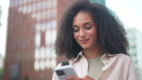 Close up of young pretty woman using smartphone while smiling on city street Stock Footage 311544026