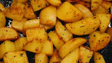 Close-up of young ruddy potatoes being fried with aromatic spices in a frying Stock Footage 320954867