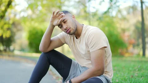 Close up of a young runner in a t-shirt overtired after a hard run sitting  Stock Footage 234875731