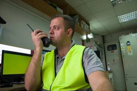 Close-up of young security guard talking on a walkie-talkie. Stock Photos