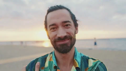 Close-up of young smiling man looking at the camera on the beach at sunrise Stock Footage 227141638
