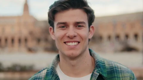 Close-up of young smiling man looking at camera on old city background Stock Footage 297616215
