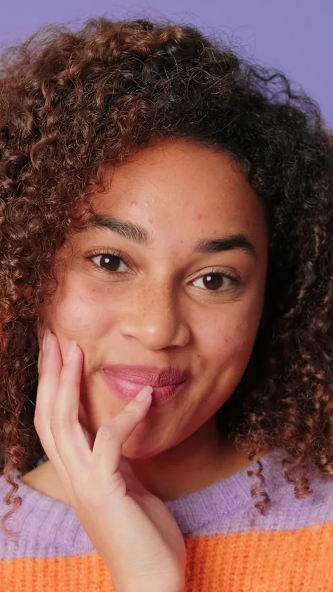 Close-up of young smiling woman looking at camera on lilac background in studio Stock Footage 283563532