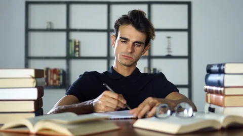 Close-up Young Student Sitting at the Table, Studying, Writting Notes, Thinking Stock Footage 93297272