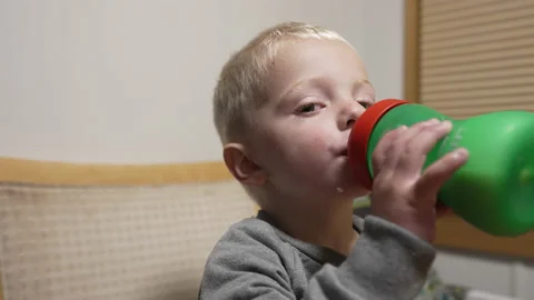 Close up of a young toddler drinking milk out of a sippy cup bottle. Slow motion Stock Footage 220231245