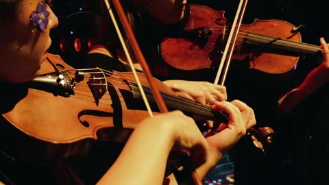 Close-up of a young violinist playing on stage under warm spotlight orchestra Video stock 301558718