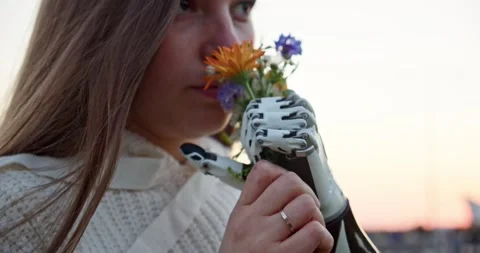 Close-up of a young woman with a bionic hand holding a bouquet of wild flowers Stock Footage 160048951