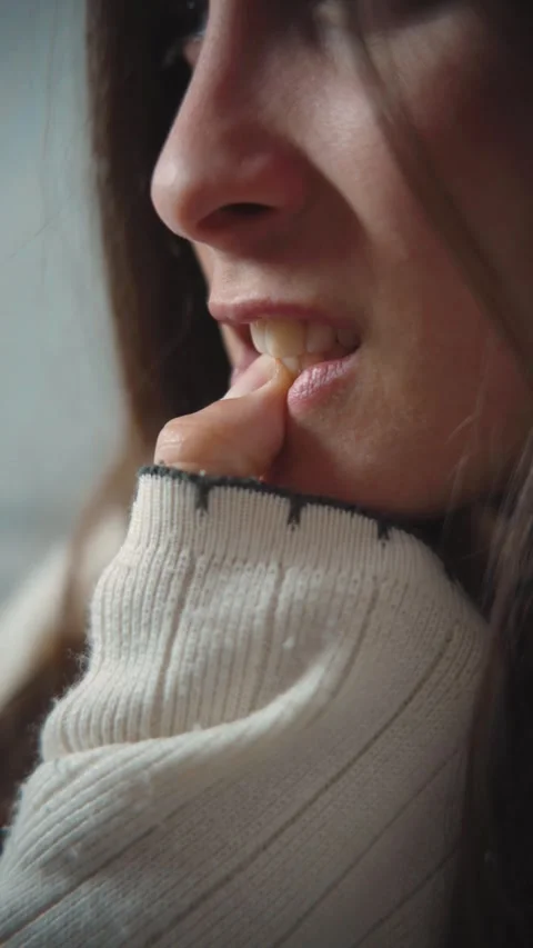 Close-up of a young woman biting her nails anxiously, representing stress, nervo Stock Footage 346162336
