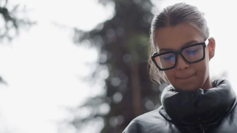 Close up young woman in black glasses dark coat outdoors trees background Stock Footage 346728362