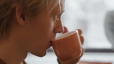 Close up of young woman drinking from orange ceramic mug with soft daylight Stock Footage 344866880