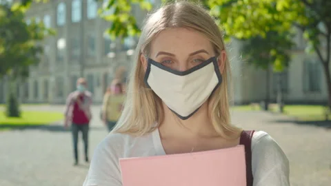 Close-up of young woman in face mask posing on university yard. Portrait of Stock Footage