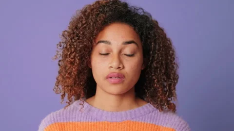 Close-up of young woman looking at camera on lilac background in studio Stock Footage 284574572