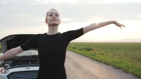 Close up young woman looking at engine of breakdown car at field tries to stop Stock Footage 112747009