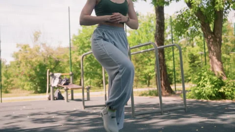Close up of young woman performing high knee exercise in bright daylight urban Video stock 345134591