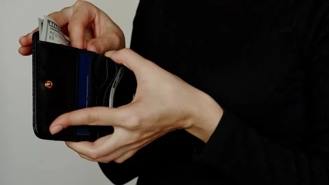 Close-up of a young woman pulling paper dollars out of a black purse. Stock Footage 305701873