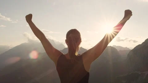 CLOSE UP: Young woman standing on the edge of the mountain with hands raised Stock Footage