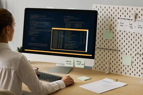 Close up young woman using computer and writing code working at desk 写真素材