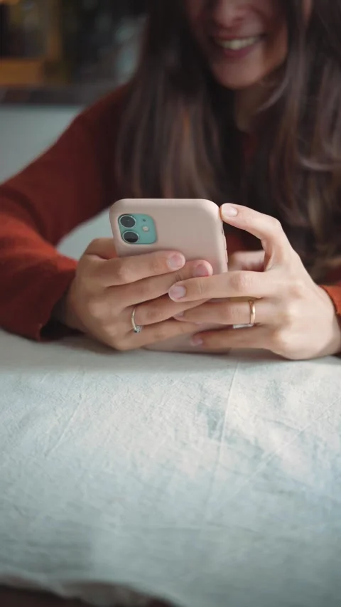 Close-up of a young woman using her smartphone at home, highlighting mobile comm Stock Footage 346321821