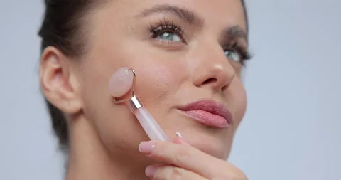Close up young woman using jade facial roller for skin care, beauty treatment on Stock Footage 169692988