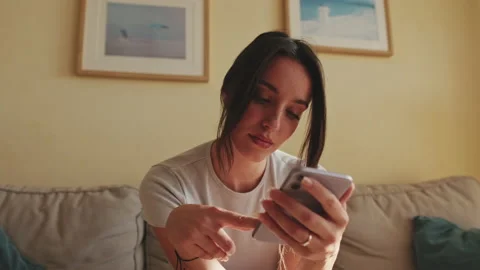 Close up, young woman using mobile phone for texting and scrolling while sitting Stock Footage 229510372