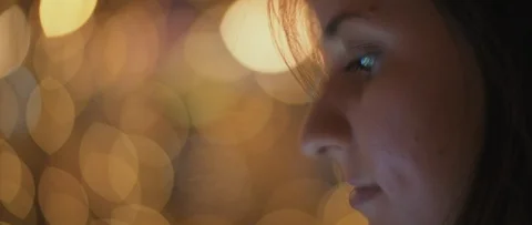 Close up of a young woman's face looking at her phone, night city bokeh light Stock Footage 123442267