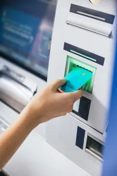 Close-up of a young woman's hand inserting a credit card into an ATM bank mac Stock Photos