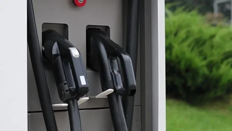 Close-up of young woman's hand puts an electric car charging port at public Stockbeeldmateriaal 212025699